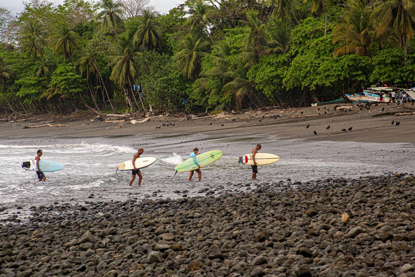 Guests carrying surfboards into the ocean at Bodhi Surf + Yoga