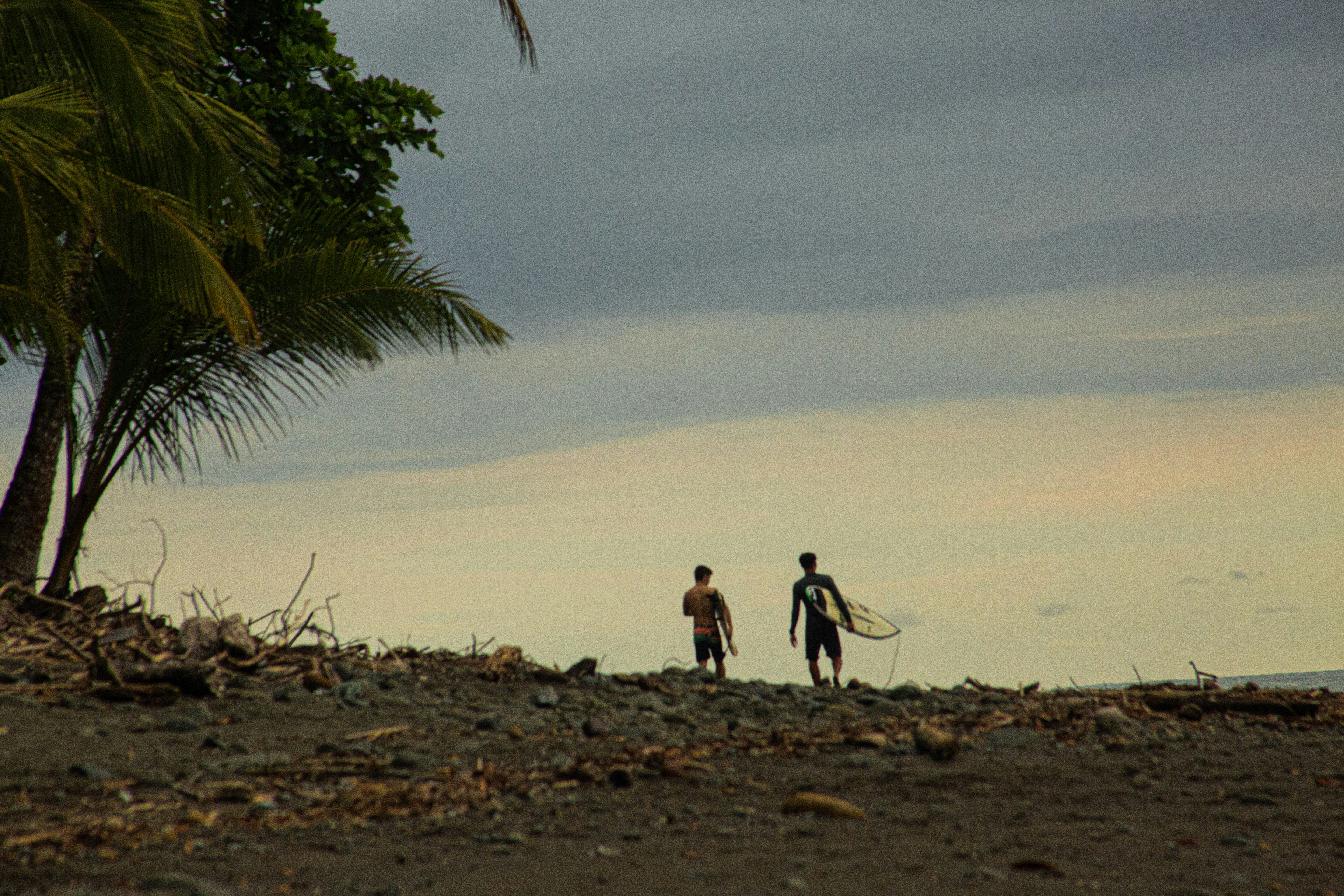 two people standing on a beach with a surfboard