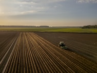 a tractor plowing a field at sunset
