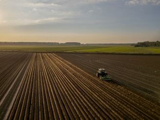 a tractor plowing a field at sunset