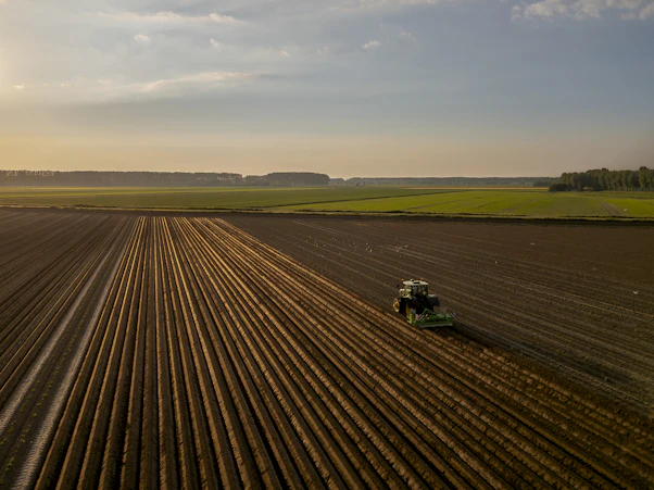 a tractor plowing a field at sunset