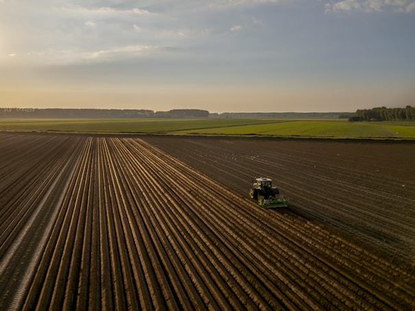 a tractor plowing a field at sunset
