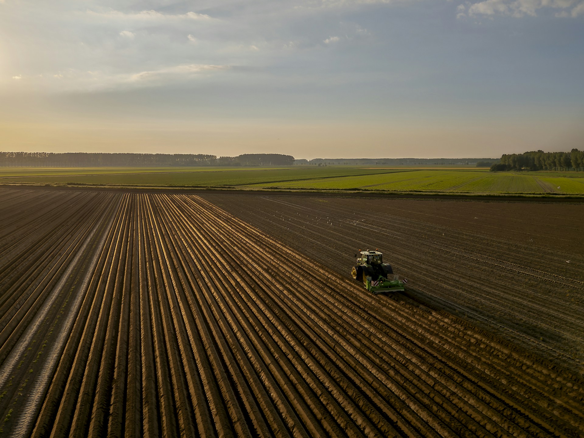 a tractor plowing a field at sunset