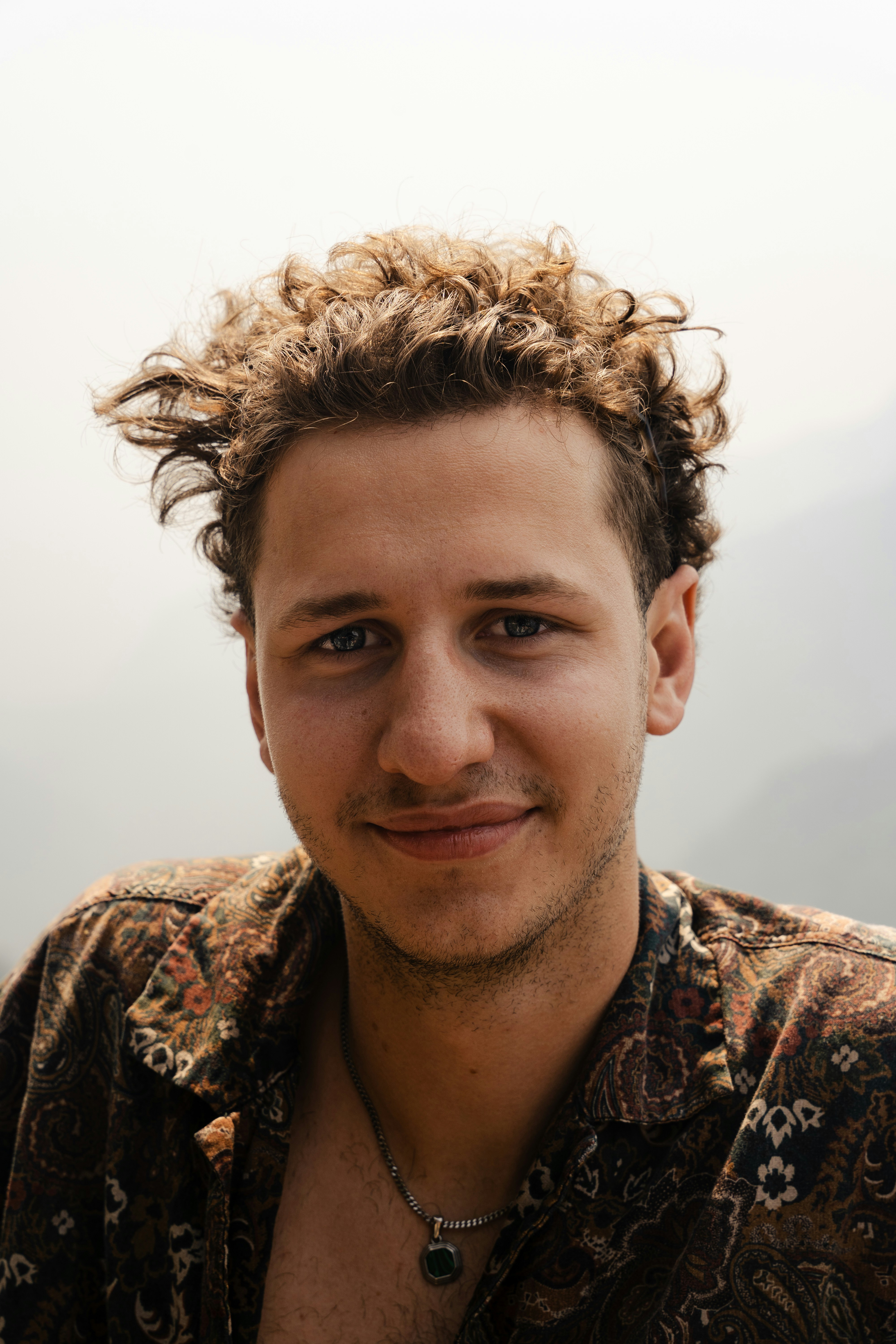 a man with curly hair smiling at the camera