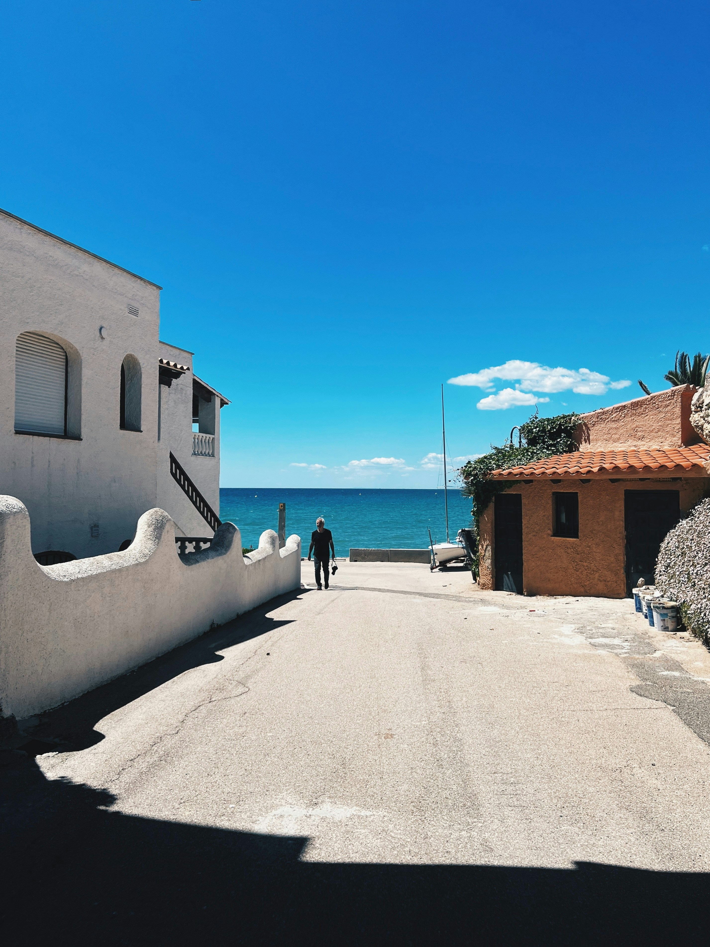 a man walking down a street next to the ocean