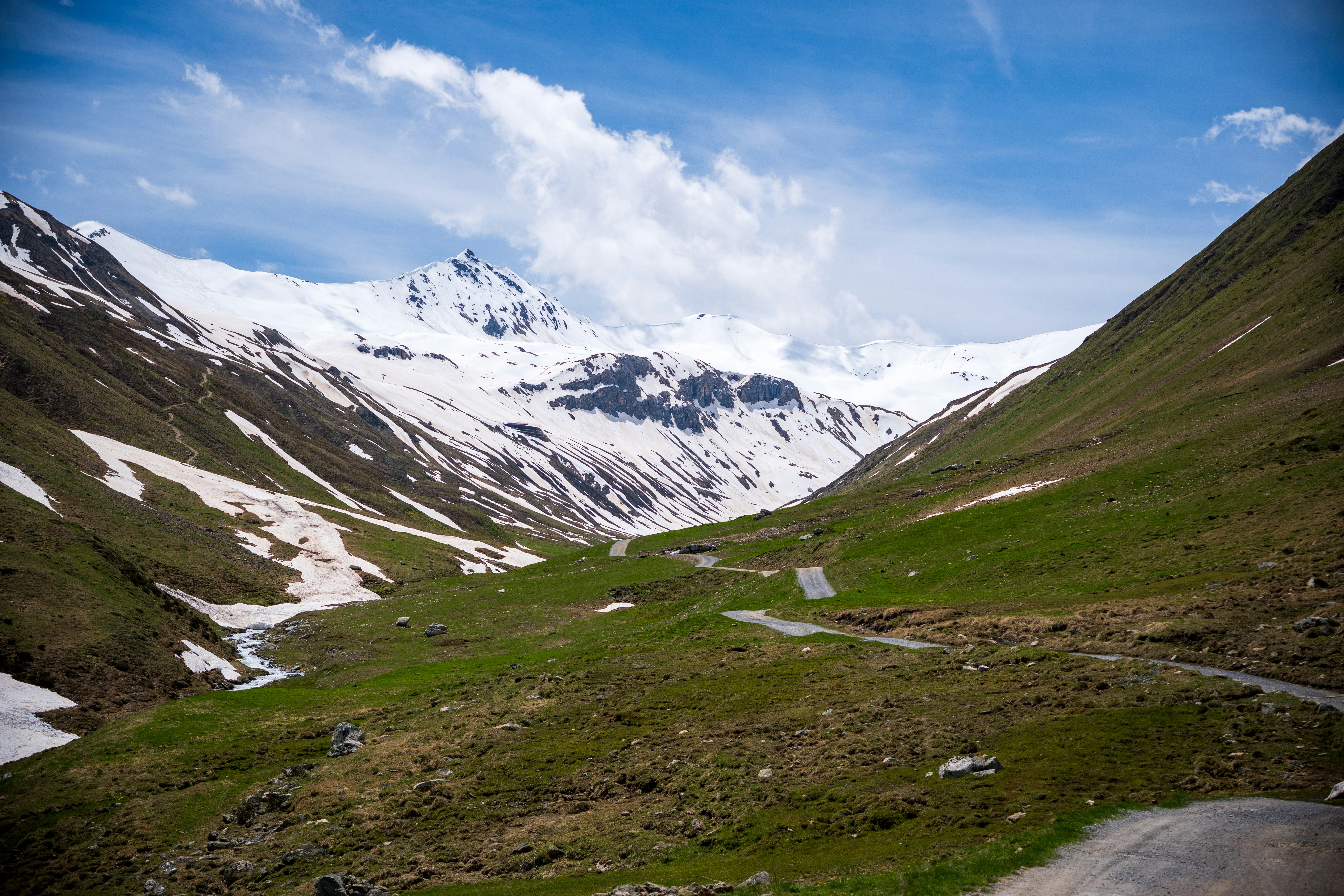 a road going through a valley with snow covered mountains in the background