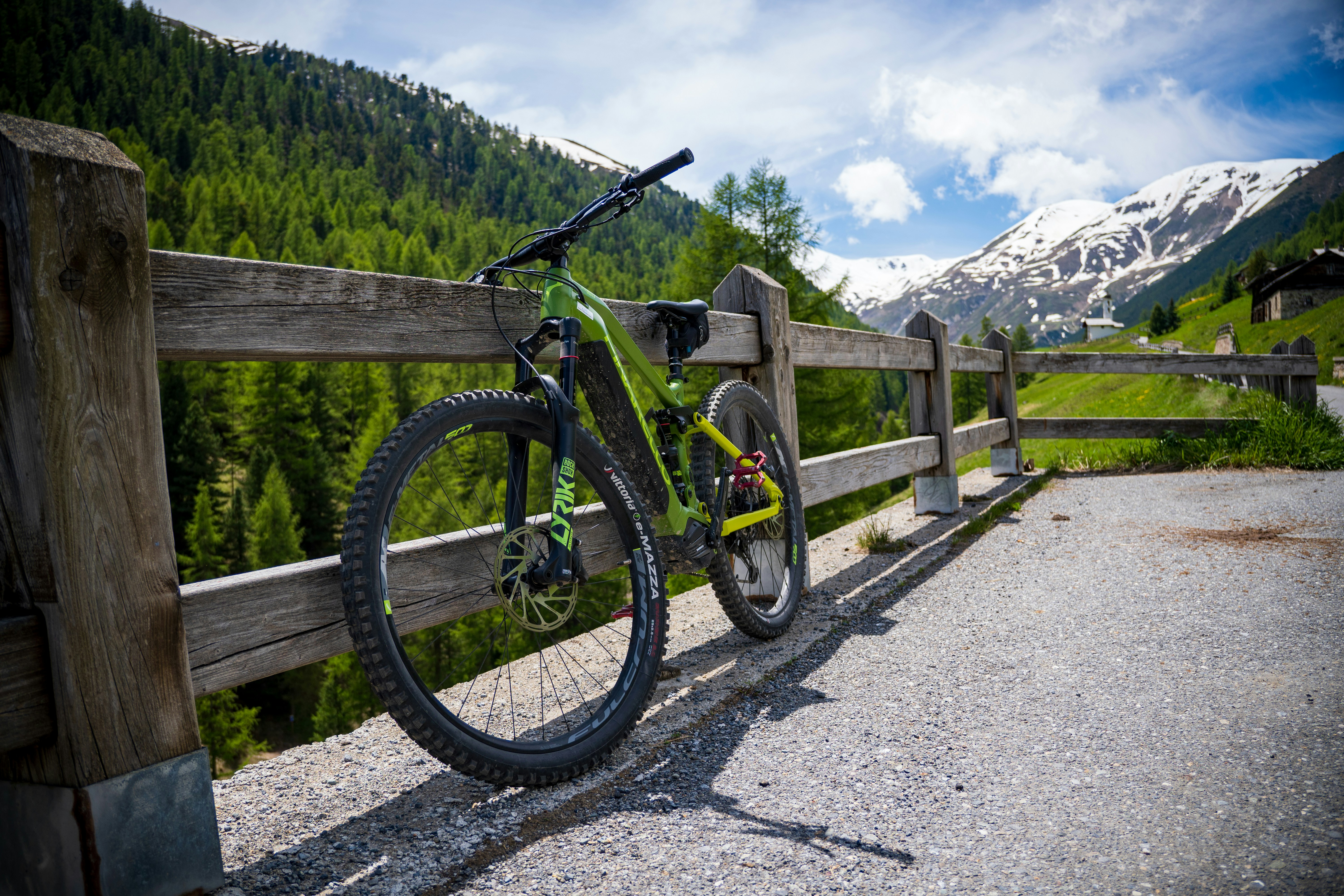a bicycle leaning against a wooden fence in the mountains