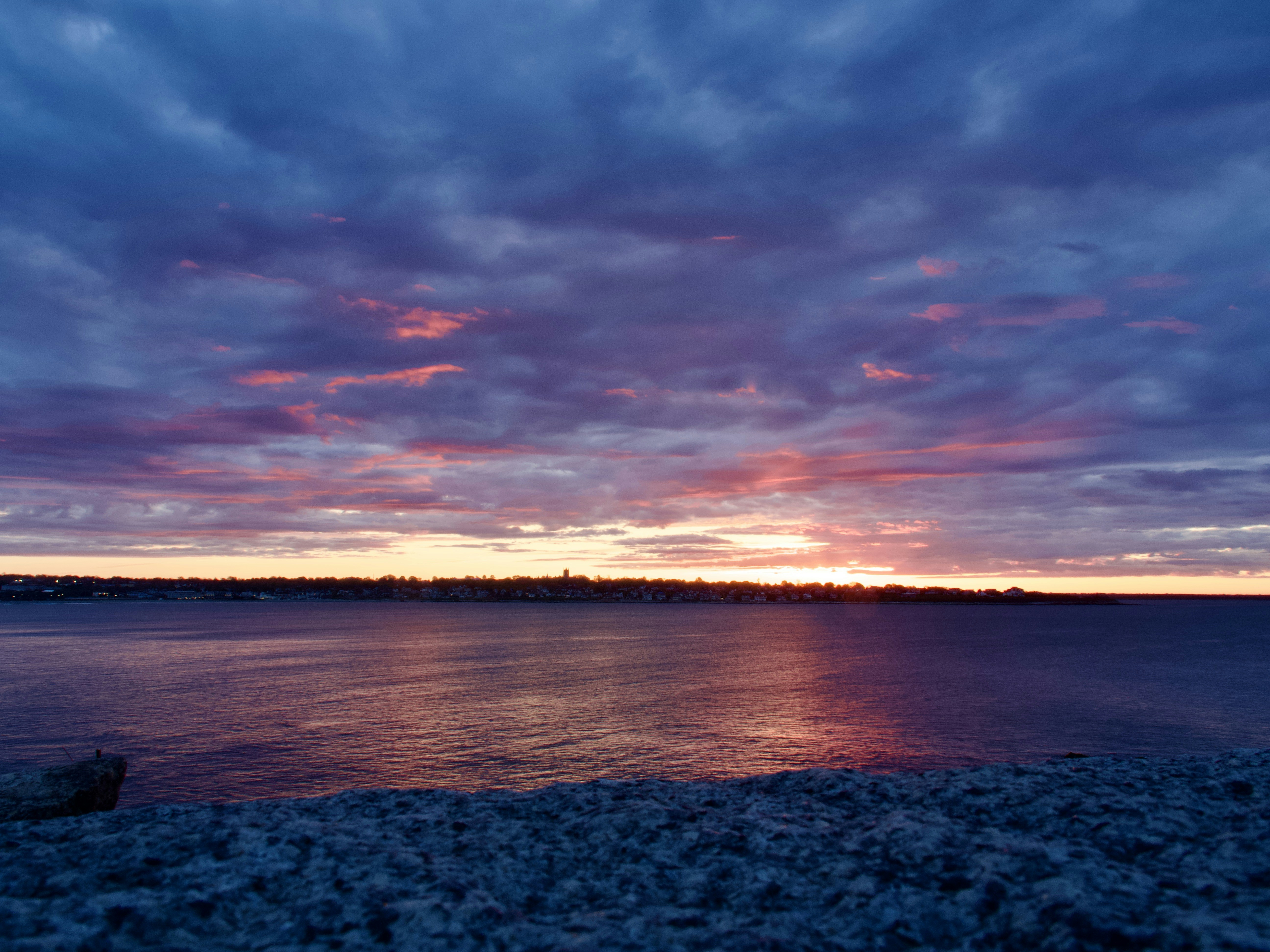 a sunset over a body of water with clouds in the sky