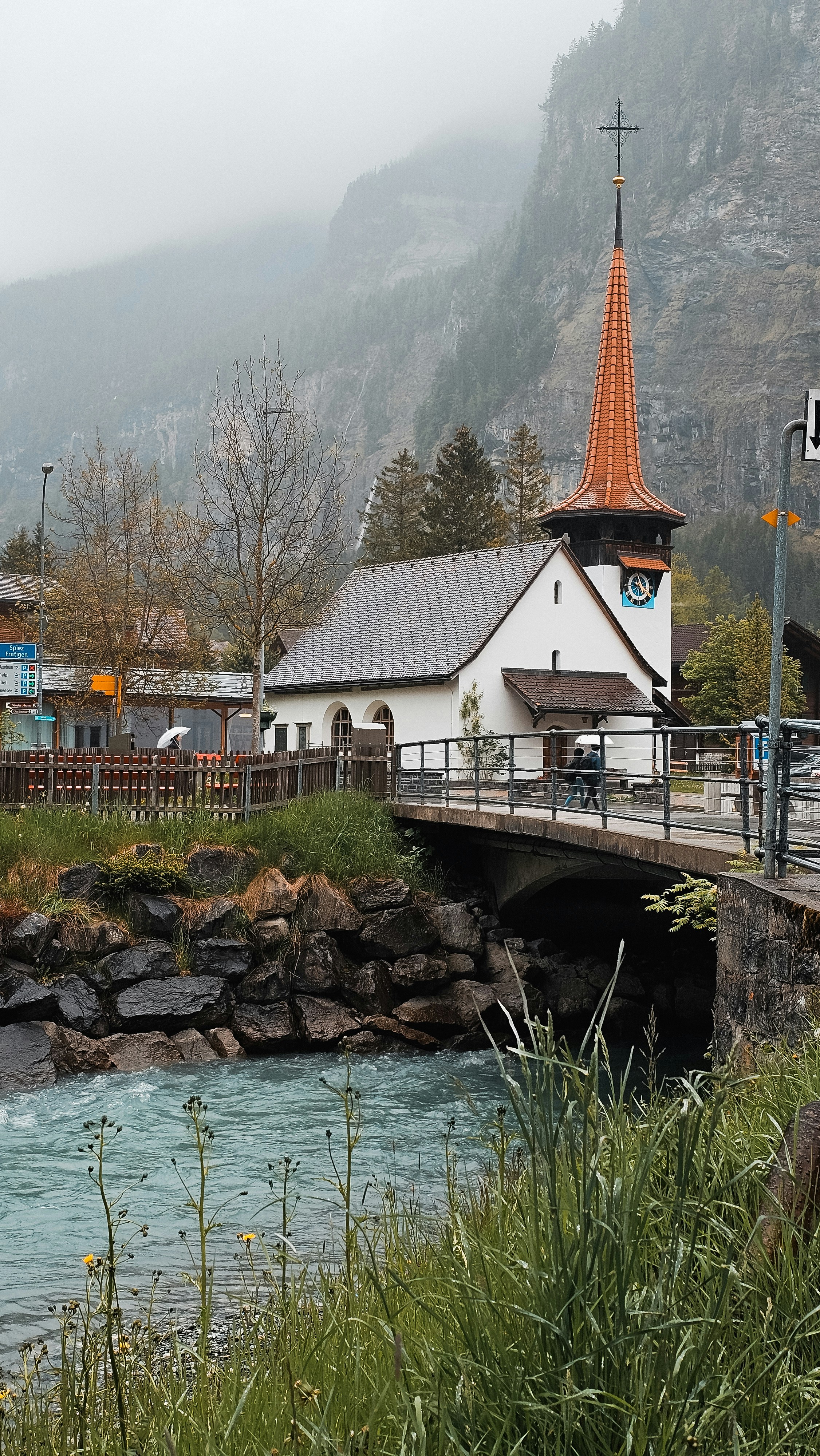 a church with a steeple next to a river