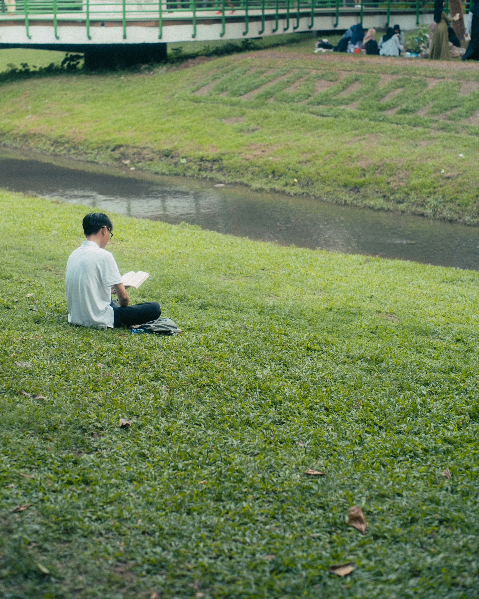 a man sitting on the grass next to a river