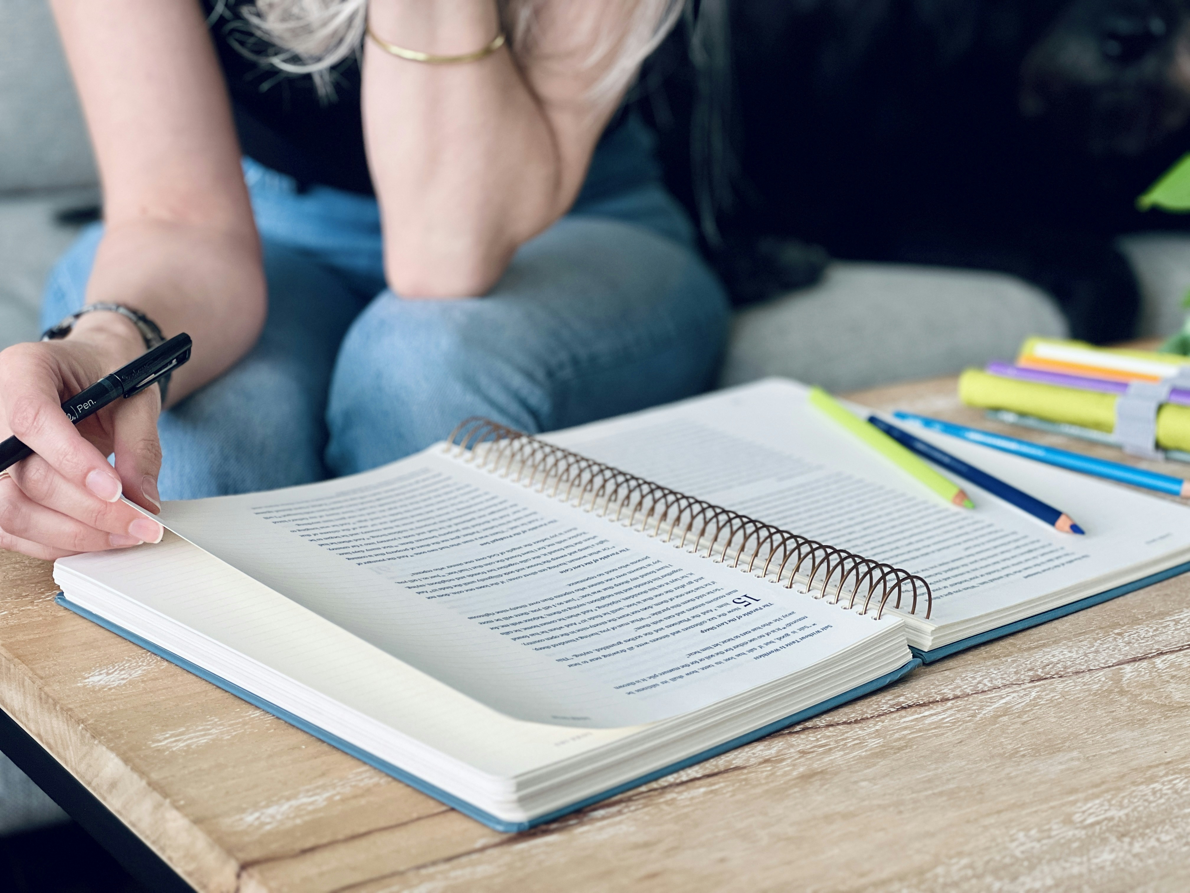 a woman sitting on a couch writing in a notebook