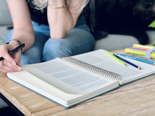 a woman sitting on a couch writing in a notebook