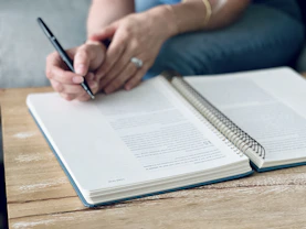 a person sitting at a table with a notebook and pen