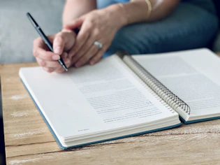 a person sitting at a table with a notebook and pen