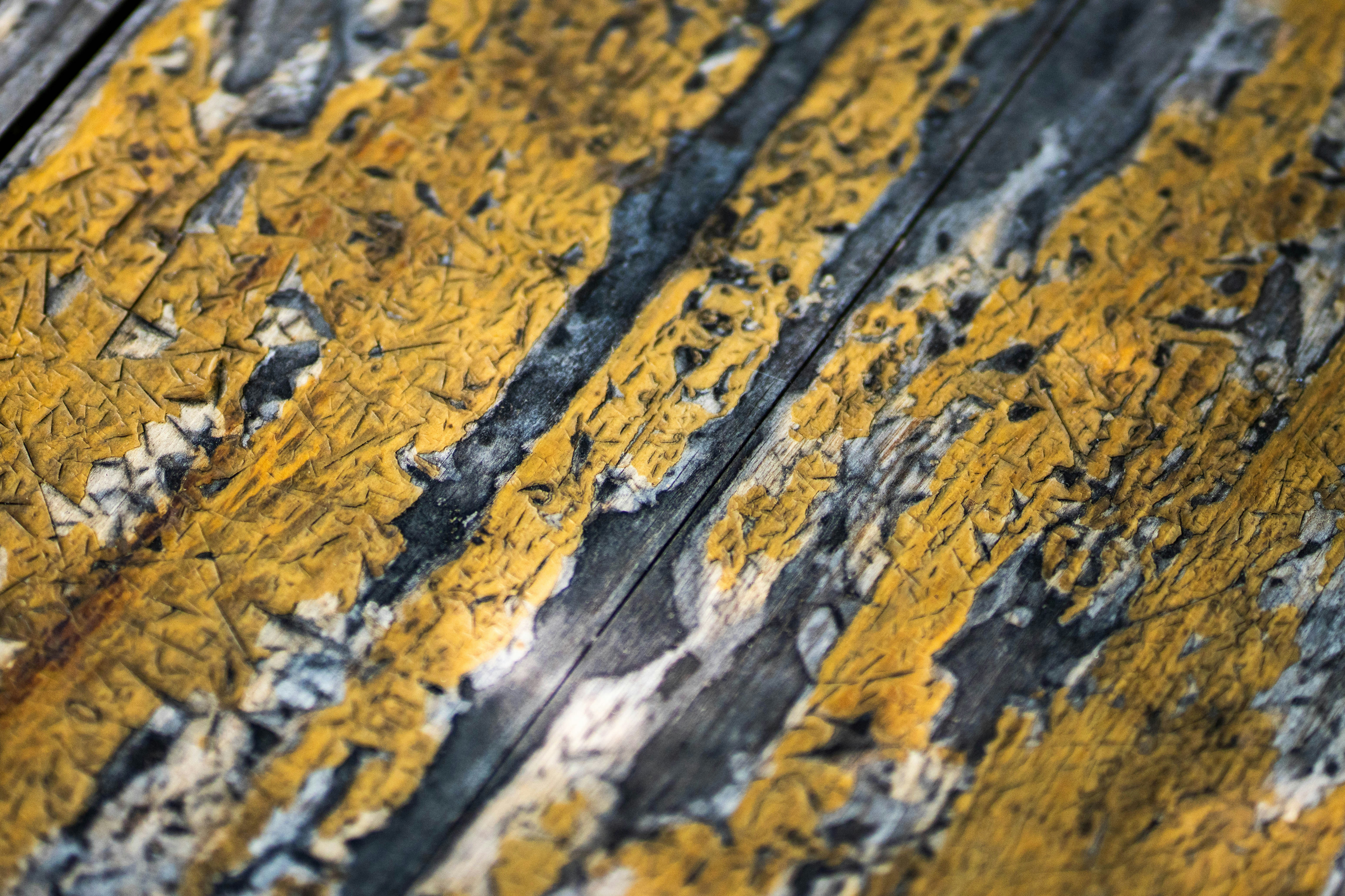 a close up of yellow and black paint on a wooden surface