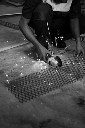 a black and white photo of a man working on a piece of metal