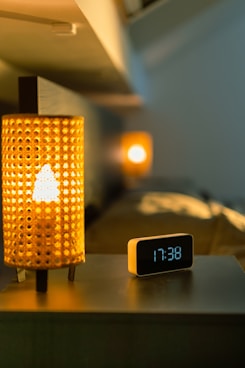 a clock sitting on top of a table next to a lamp