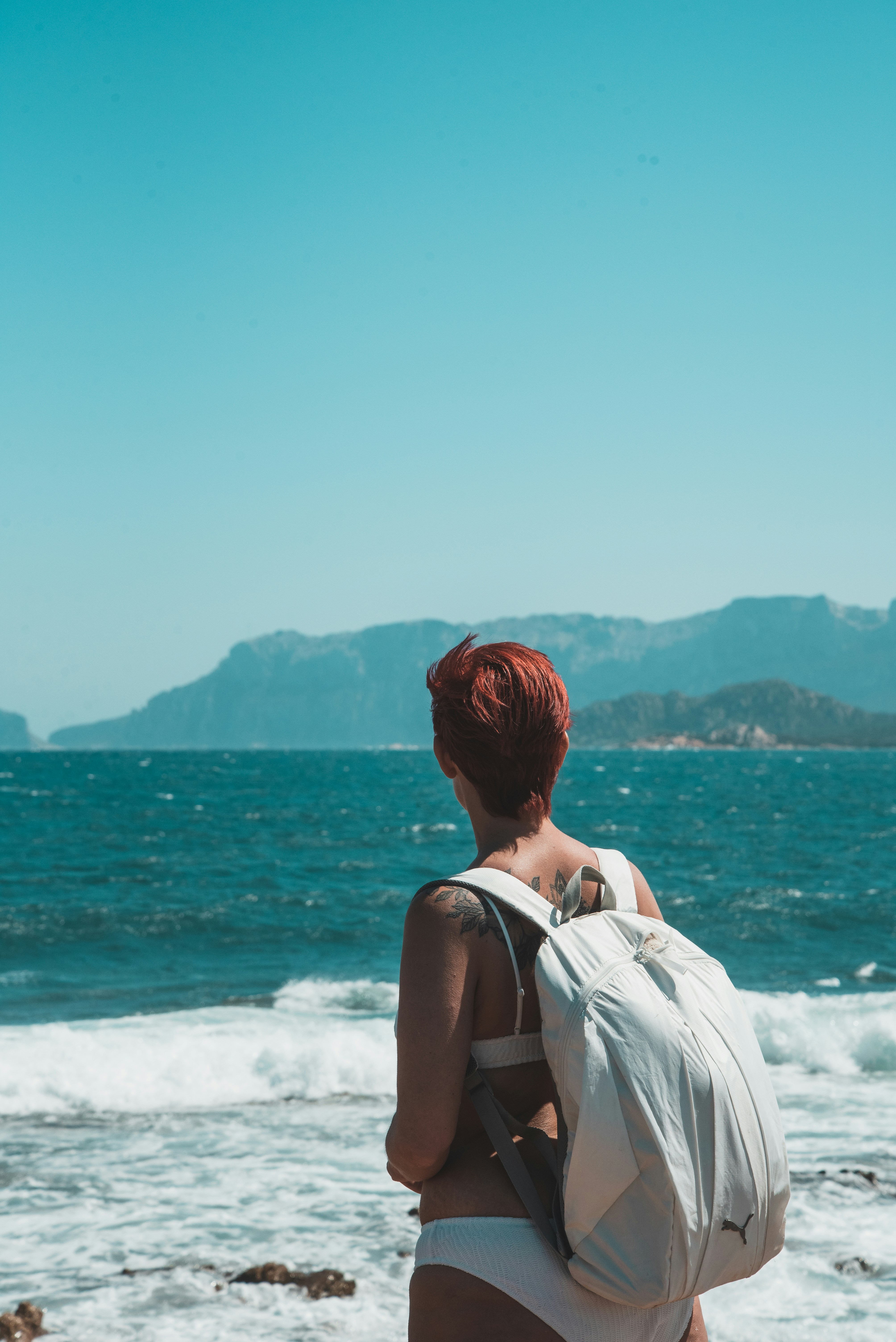 a woman with a backpack is standing on the beach