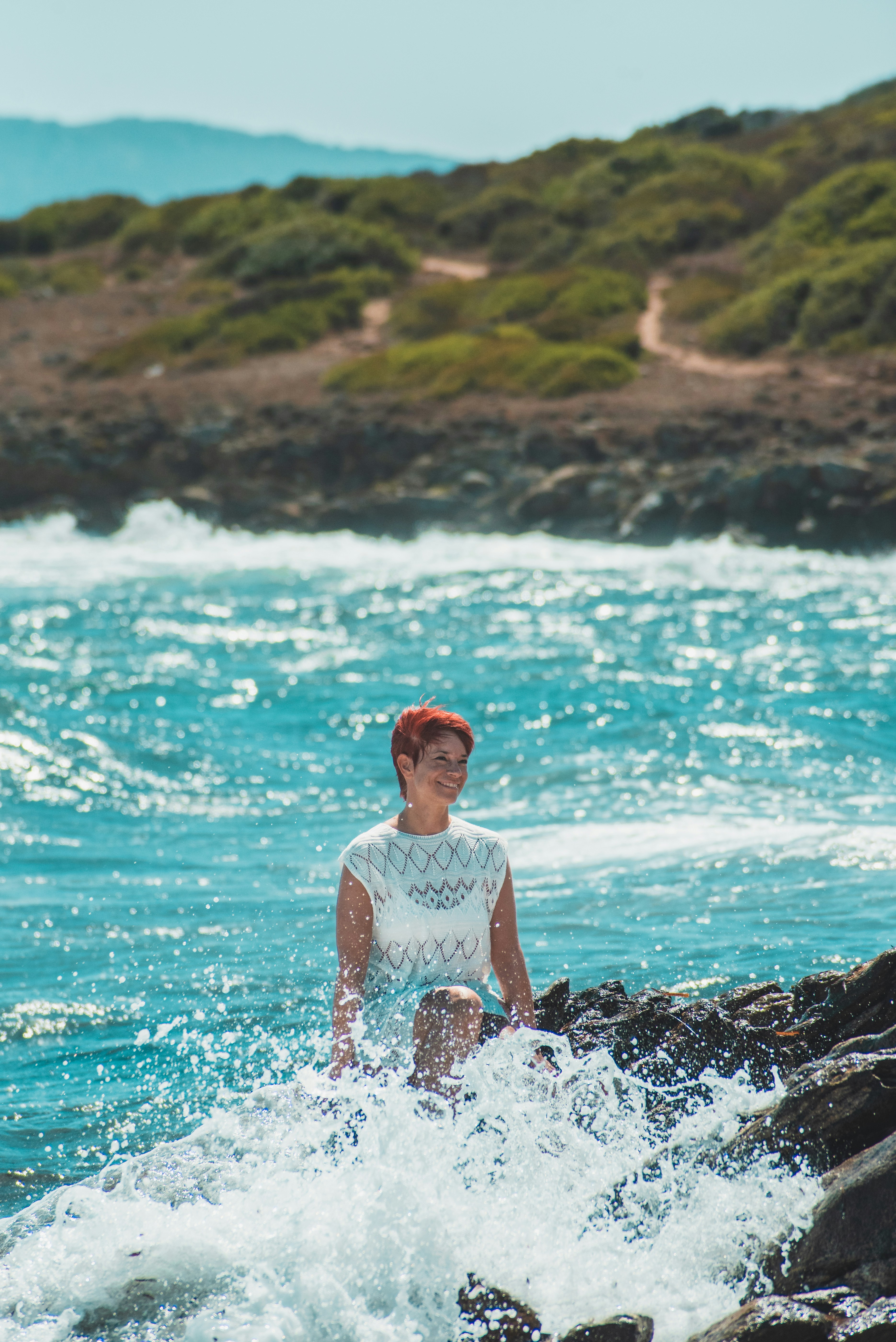 a woman standing on a rock in the ocean
