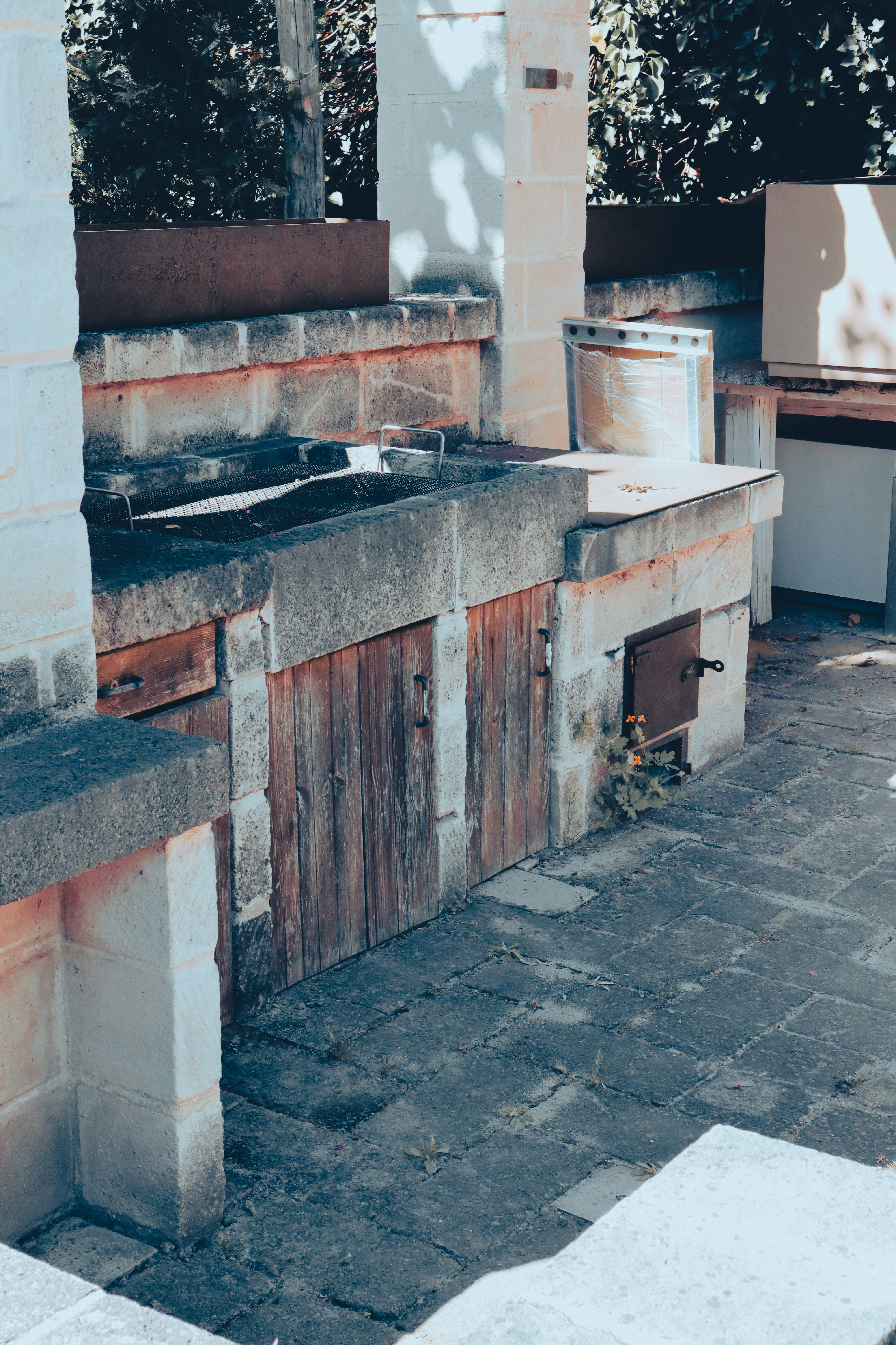 Stone outdoor barbecue grill with flowers growing from a metal oven.