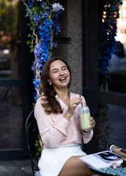 a woman sitting at a table with a drink in her hand