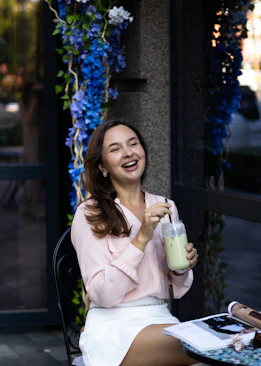 a woman sitting at a table with a drink in her hand