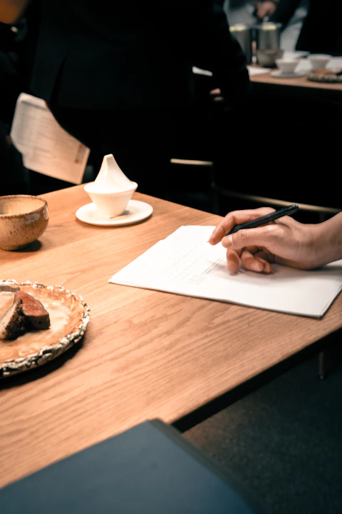 a person sitting at a table writing on a piece of paper