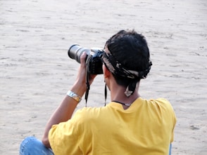 a person sitting on a beach taking a picture with a camera