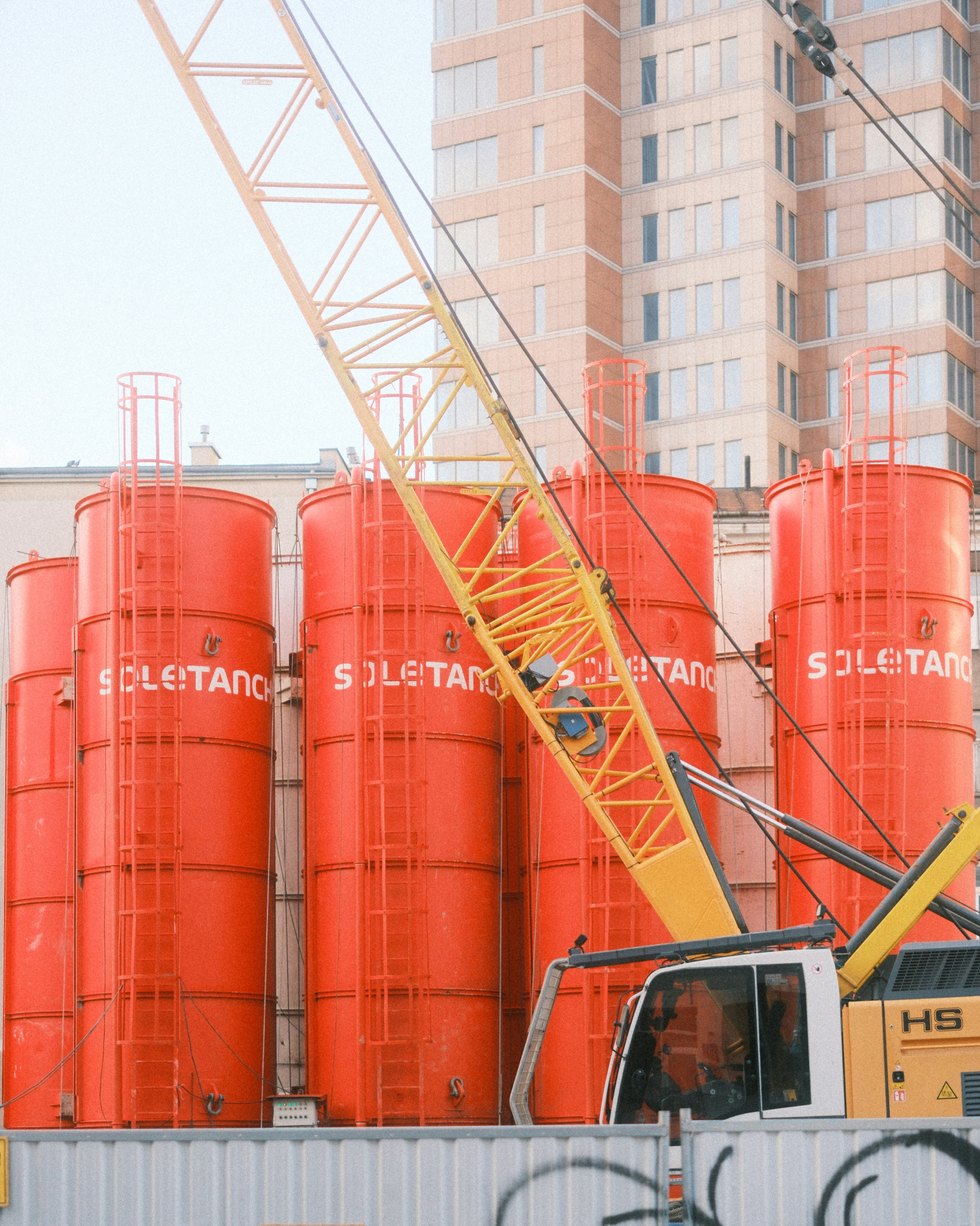 a crane is lifting a large orange tank
