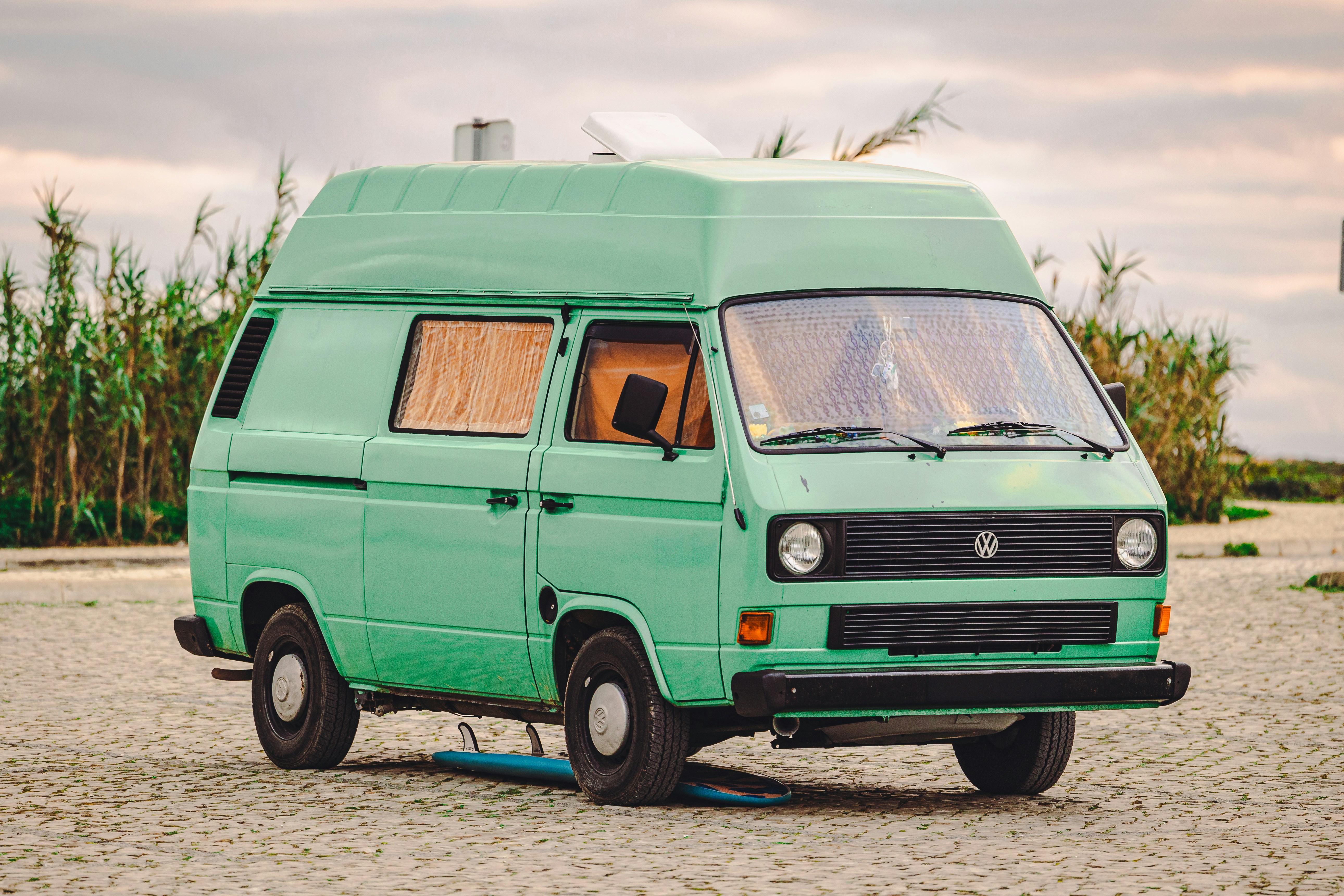 a green van is parked on the beach