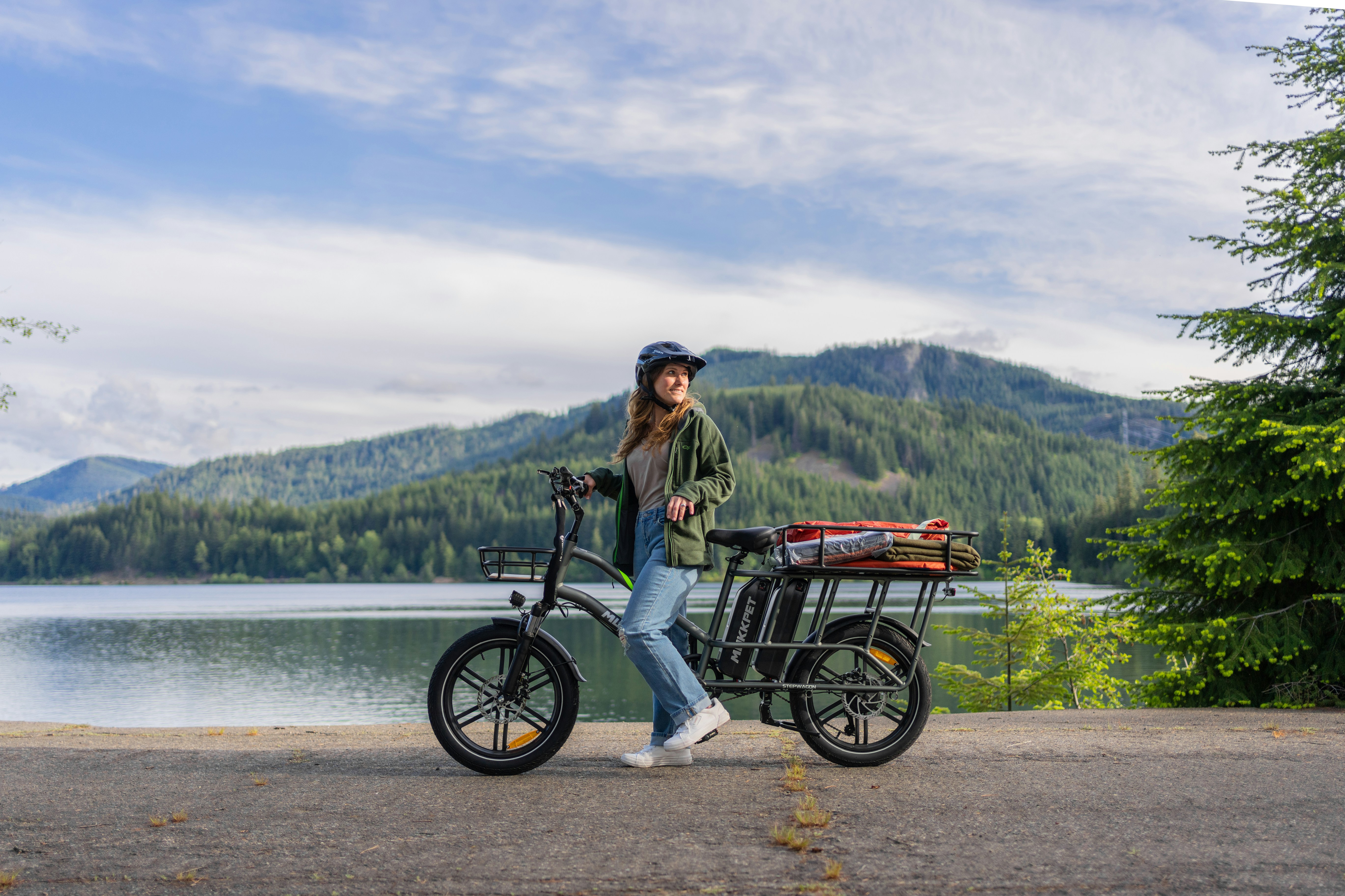 Una mujer de pie junto a una bicicleta cerca de un lago