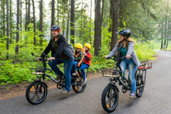 a family of three riding bikes down a road
