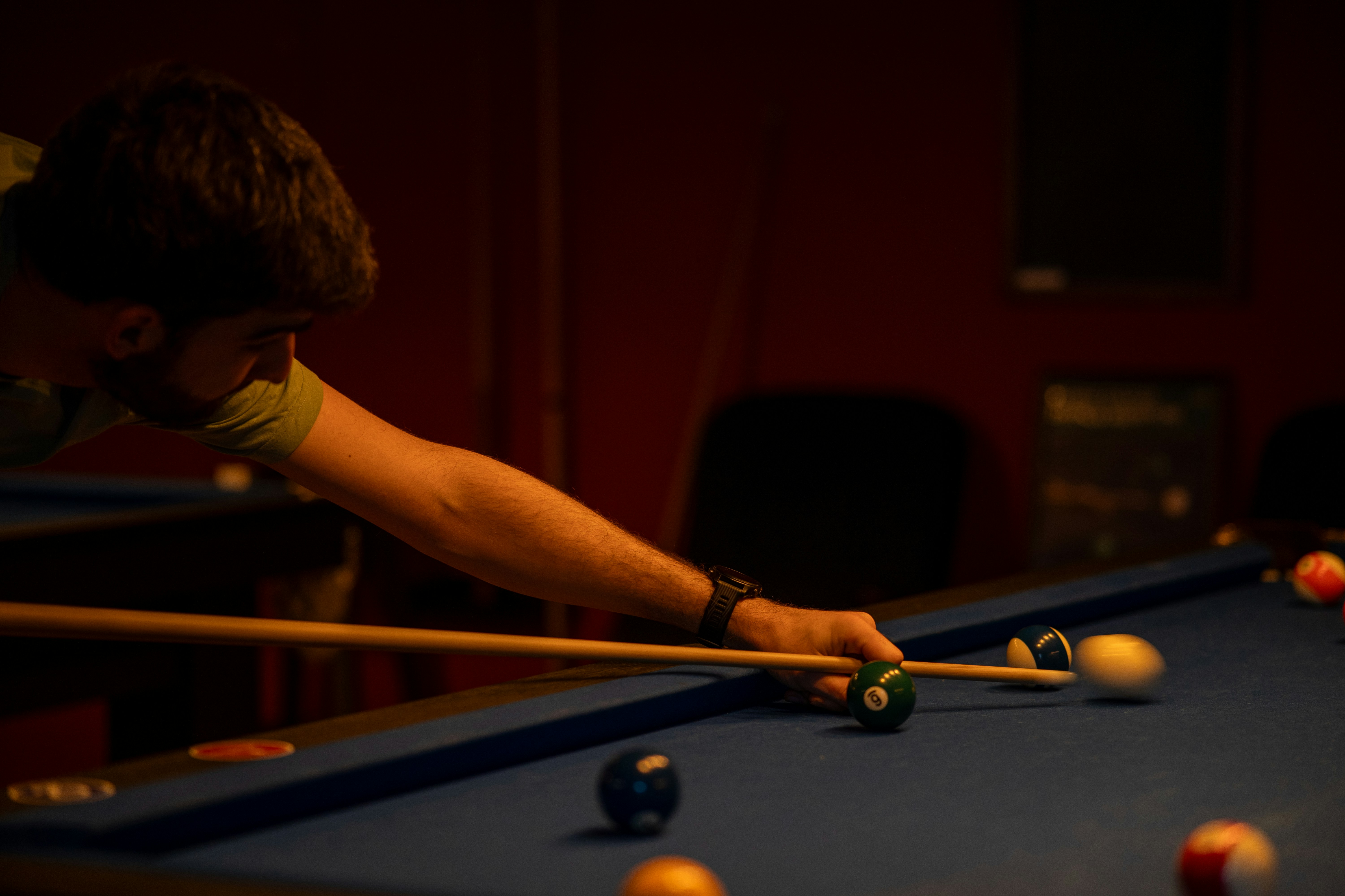 a man leaning over a pool table with a cue in his hand