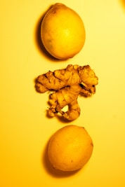 two lemons and a ginger on a yellow surface