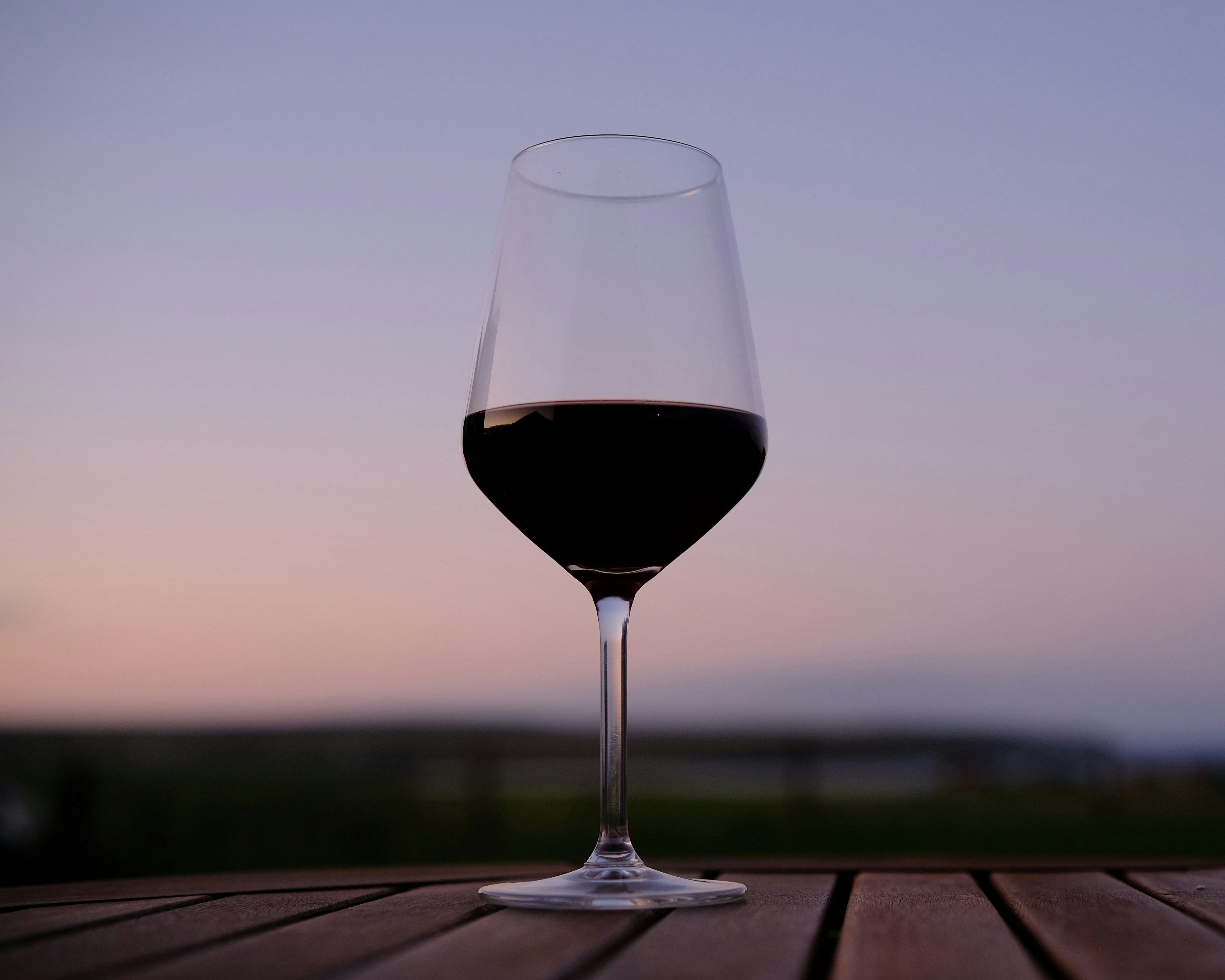 a glass of wine sitting on top of a wooden table, Please enjoy this picture captured in The Outer Hebrides, UK. Photographed with a Fujifilm X-T3. For all enquiries, please contact me via Unsplash and I will endeavour to reply as soon as possible. Have a great day! [Rory Tucker / The Yorkshire Photographer]