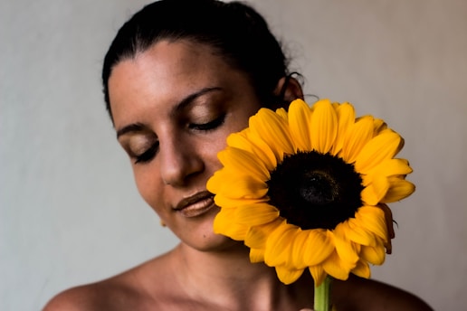 a woman holding a sunflower up to her face