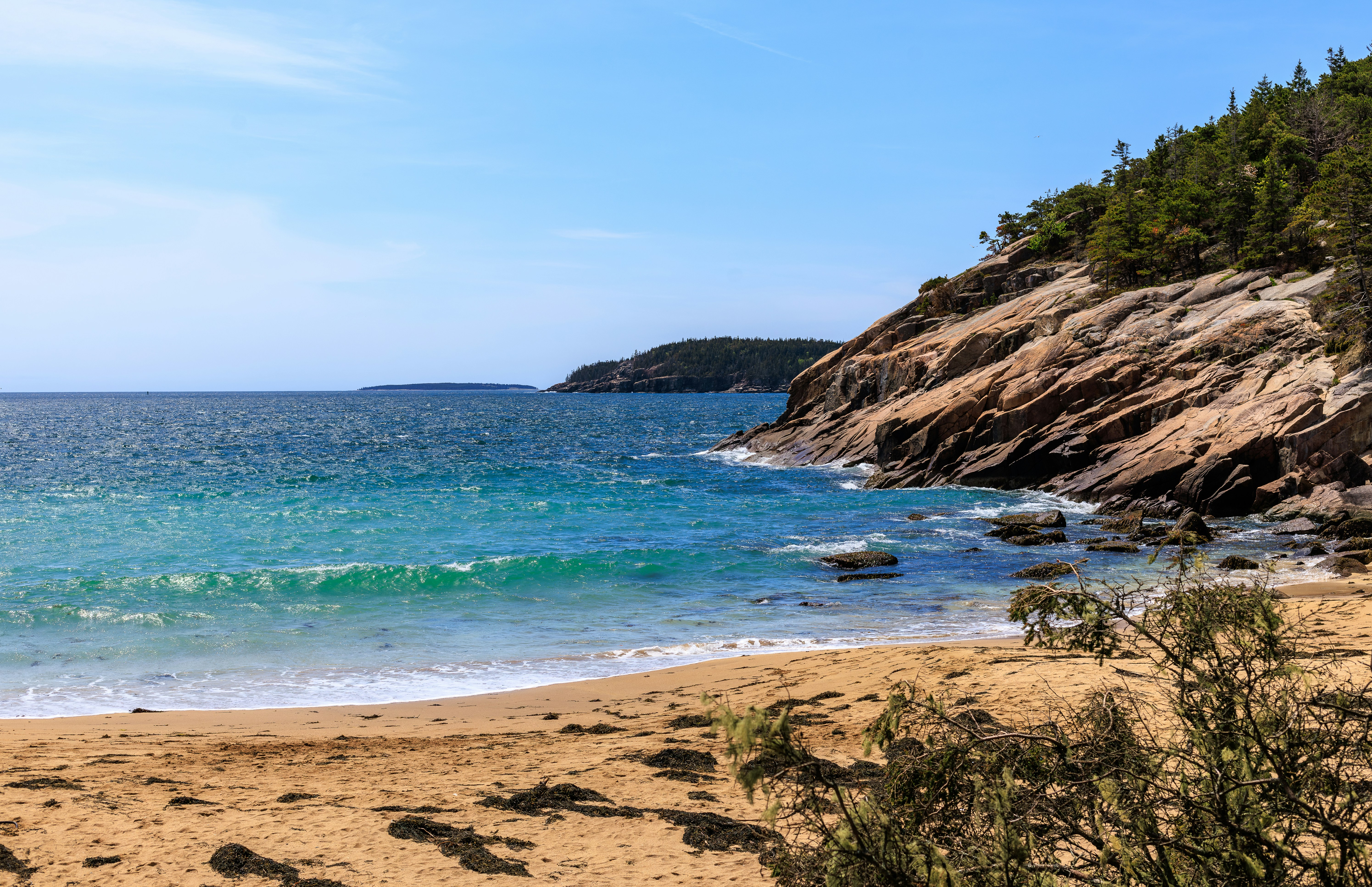 a sandy beach next to a rocky cliff, M1/M2 MacBook Pro aspect ratio. Taken in May of 2024.
