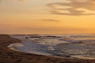 a person riding a surfboard on top of a sand beach