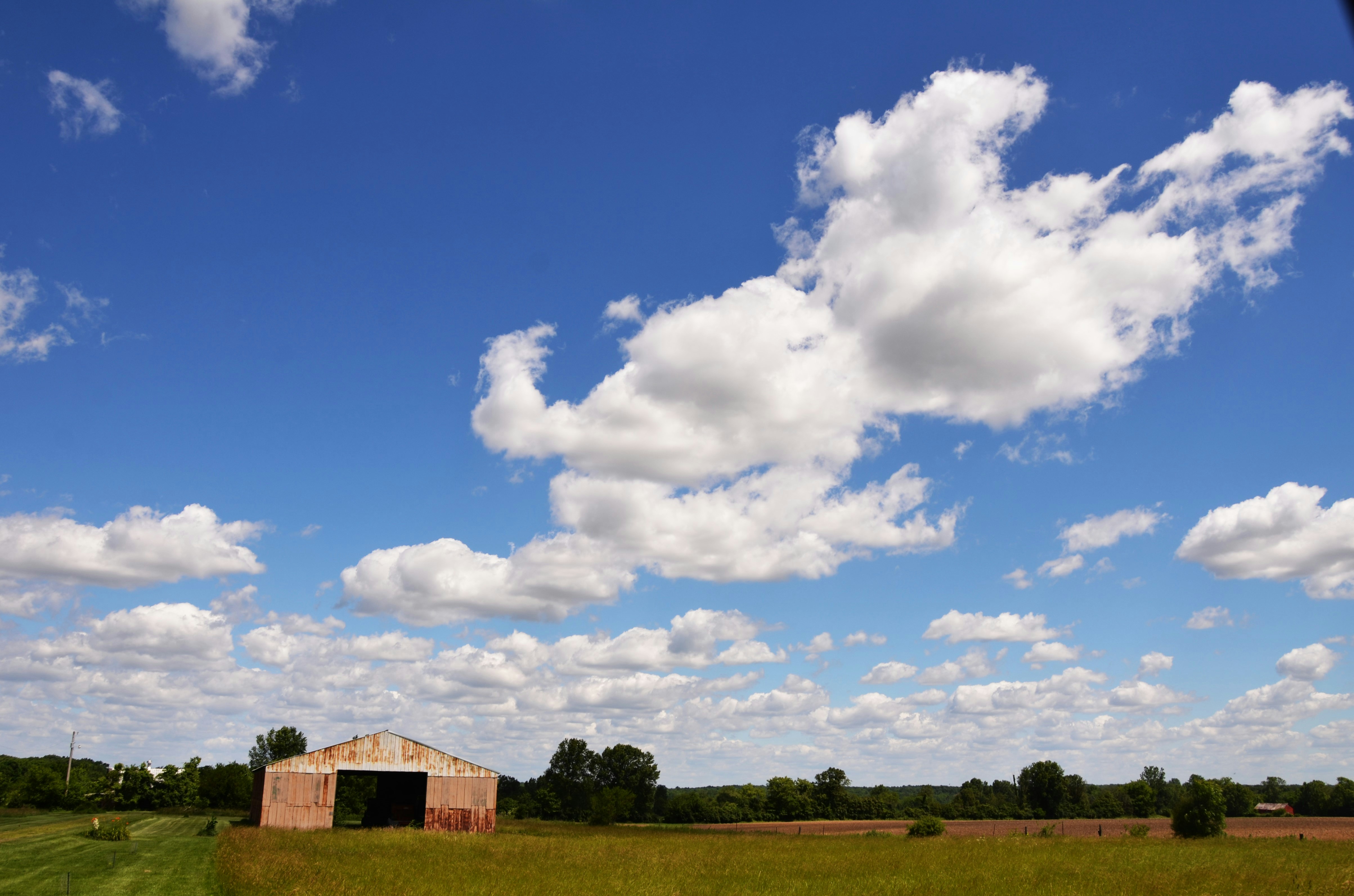 A field with a barn and clouds in the sky photo – Free Blue Image on ...