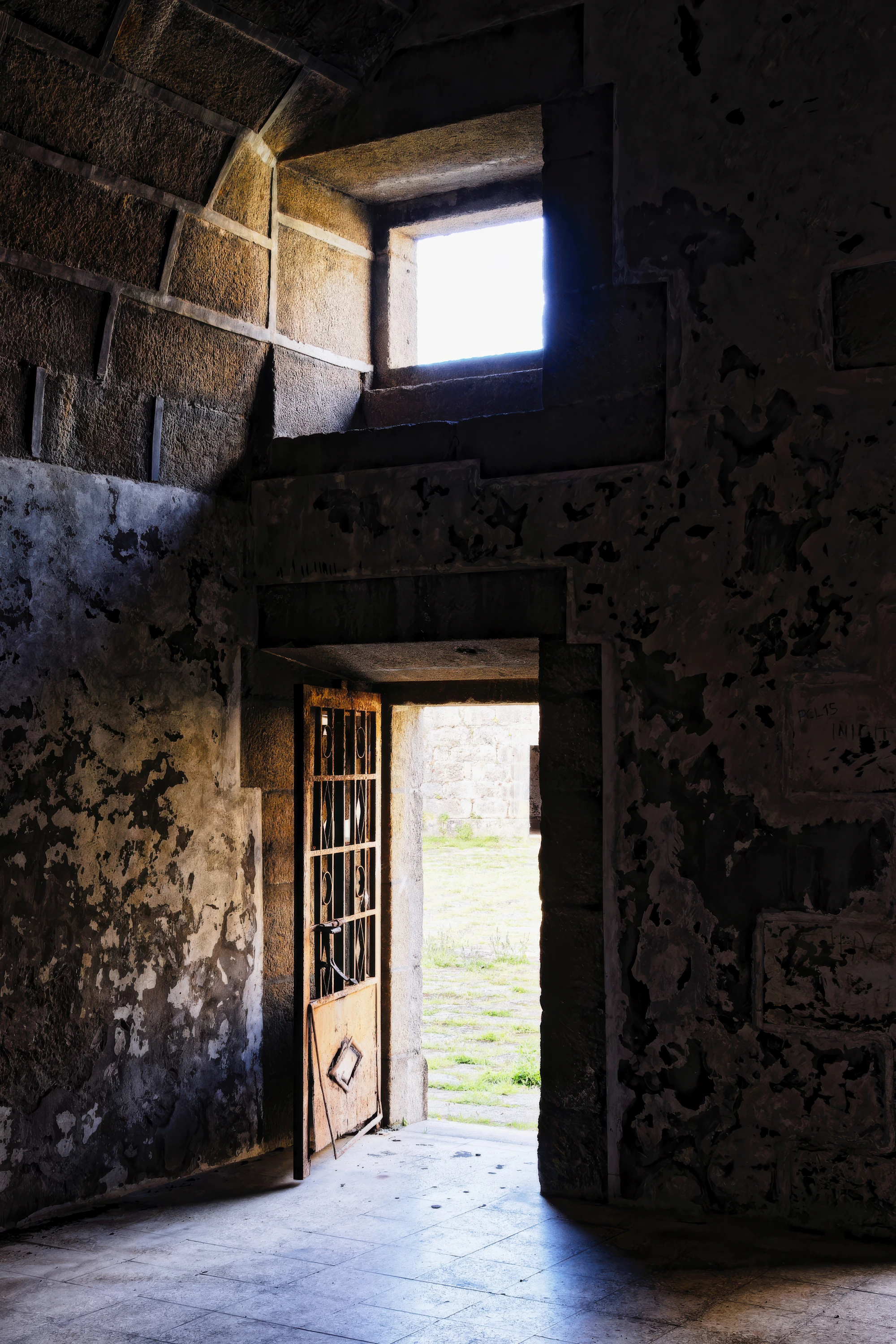 An open doorway in a dark wall looking out onto a bright green field