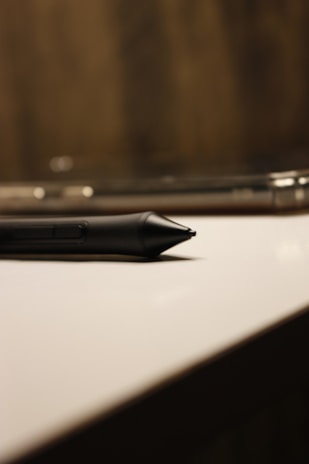 a black pen sitting on top of a white table
