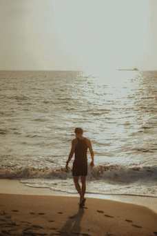 a man walking along a beach next to the ocean