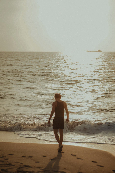a man walking along a beach next to the ocean
