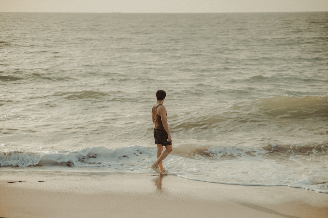 a man walking along a beach next to the ocean,
