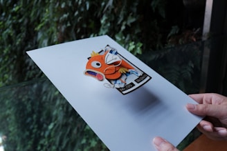 a hand holding a piece of paper with a picture of a fish on it