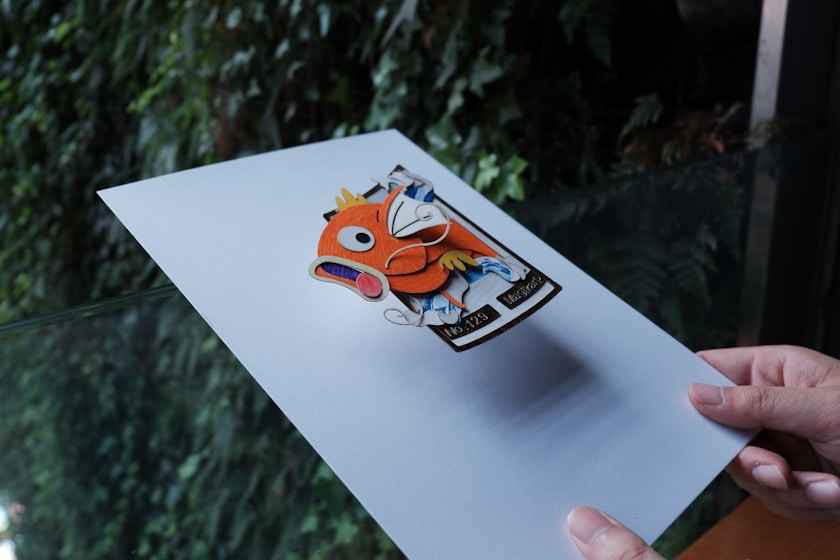 a hand holding a piece of paper with a picture of a fish on it