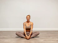 a woman sitting on the floor in a yoga pose
