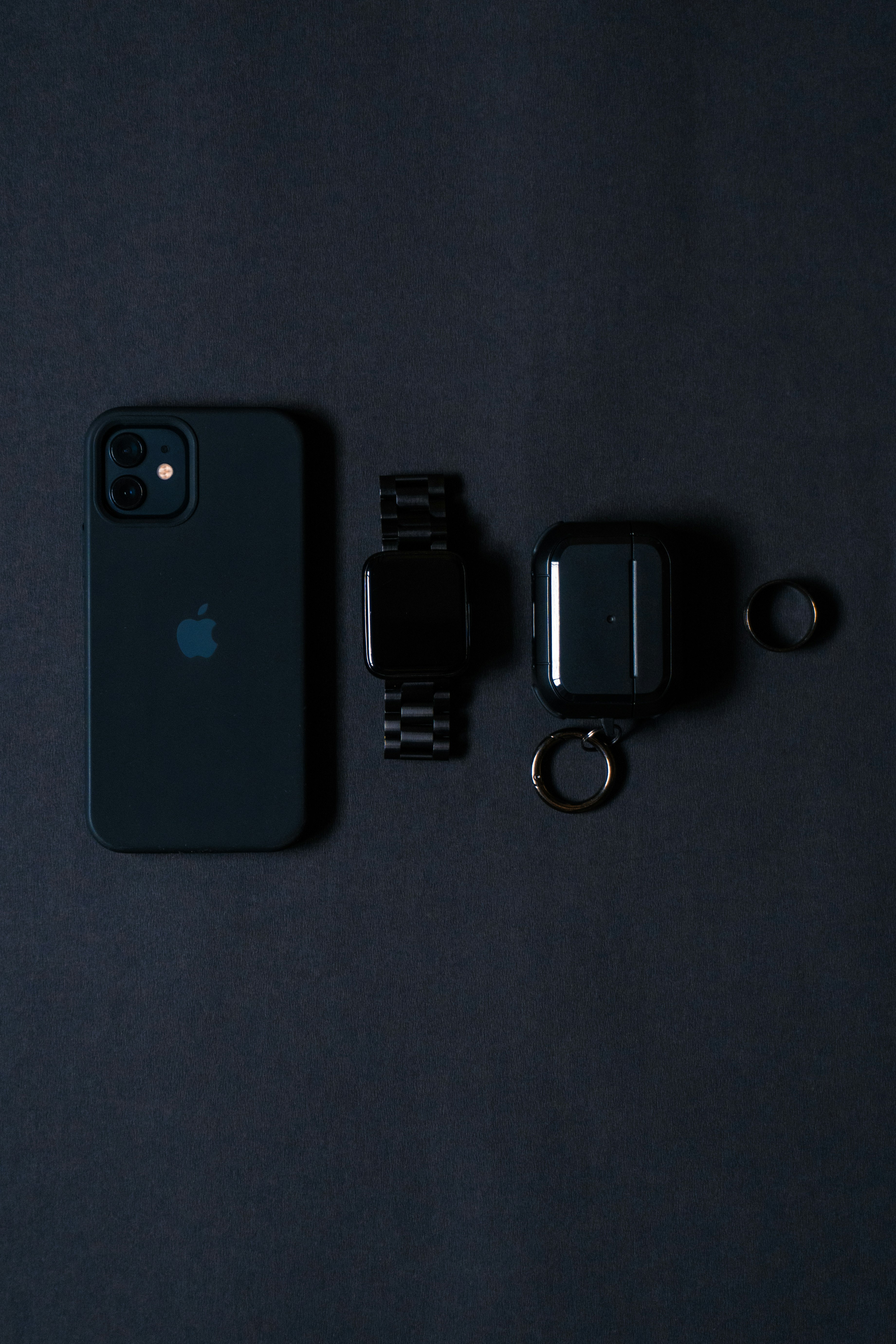an iphone, watch, and earbuds on a black surface