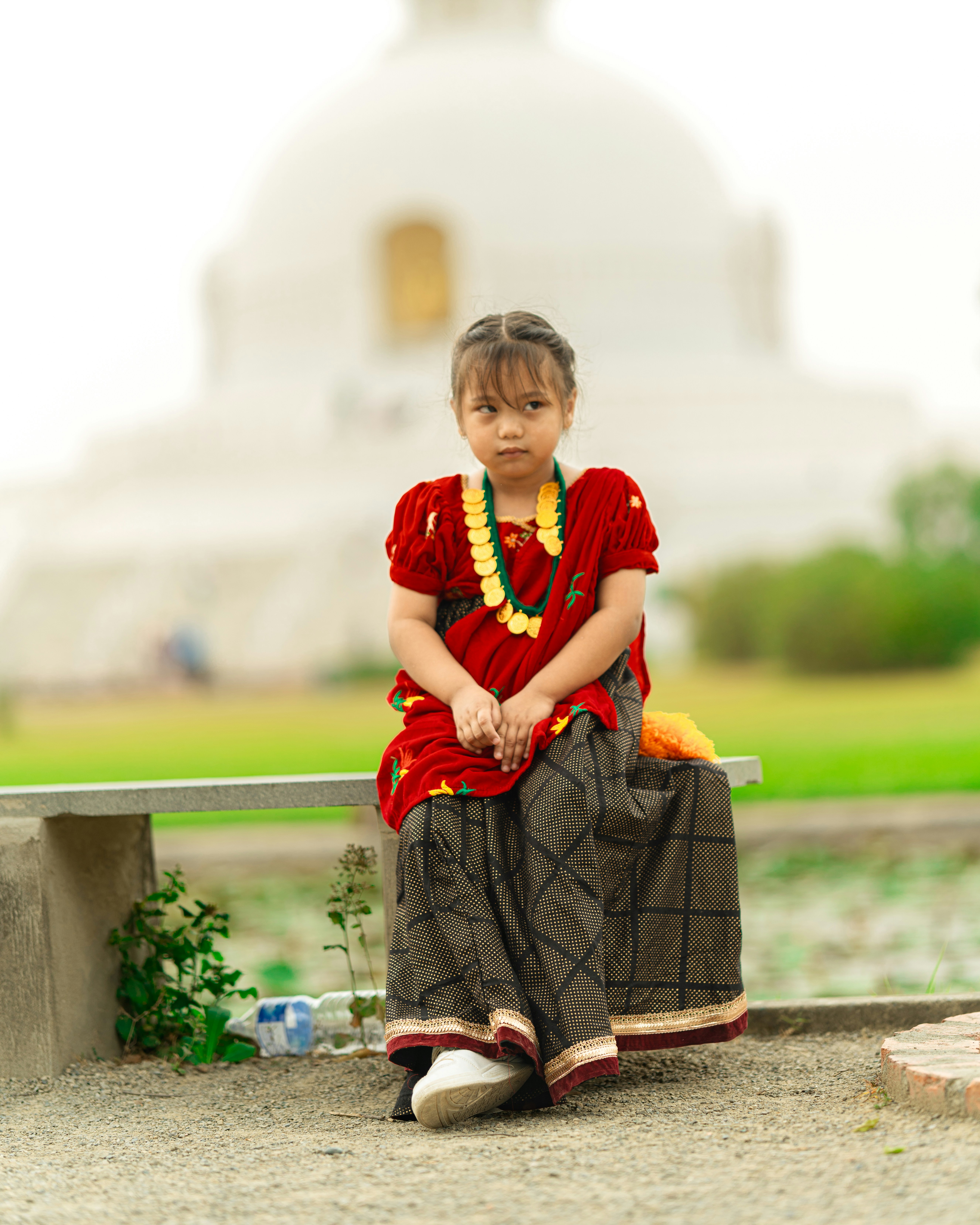 a young girl sitting on a bench in front of a building