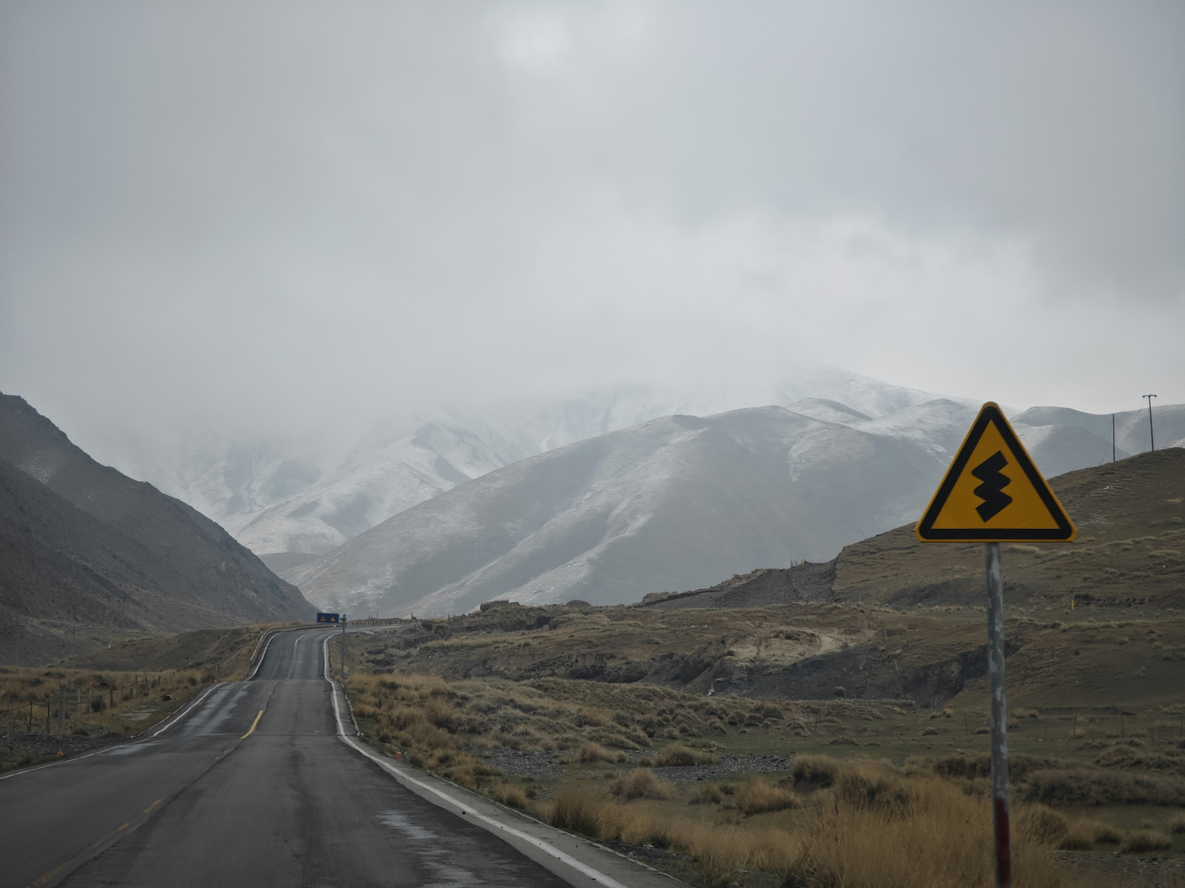 a road sign on the side of a road with mountains in the background
